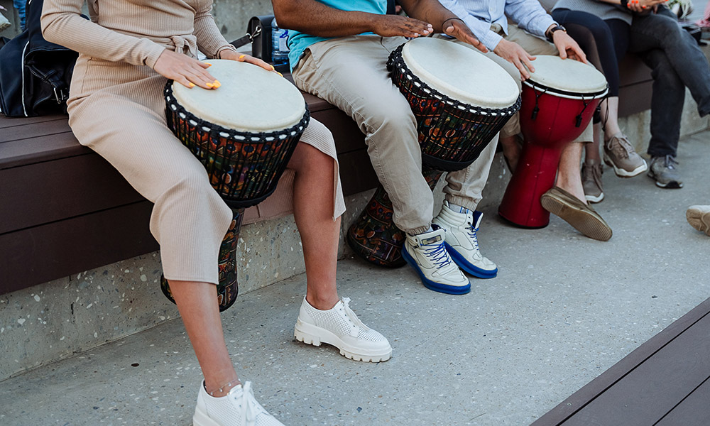 A group of people play drums on the streets of the city, hands beat the rhythm on the djemba, street musicians, a trio of percussion, a performance in the park. High quality photo